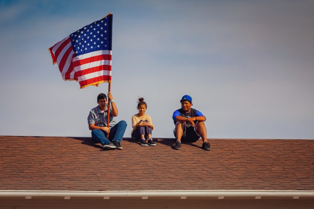 men and woman sitting on roof top holding American flag